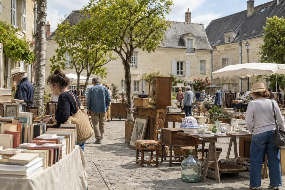 Brocante illustrative sur une place bordée de pierre claire et de toits d’ardoise