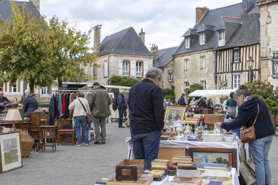 Vide-greniers illustratif dans un décor de maisons en pierre et à colombages